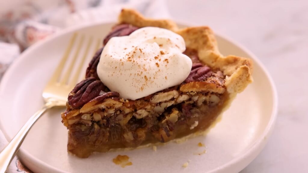 Pecan pie slice topped with whipped cream