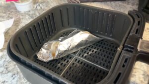 A Tortilla Wrapped Around a Foil Mold Placed Inside an Air Fryer Basket, Ready to Cook