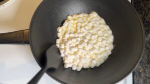 Mini Marshmallows Melting in Butter in A Black Pan with A Spatula Stirring