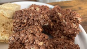 Sliced Chocolate-Flavored Protein Rice Krispie Treats Stacked on A Plate with Vanilla Ones in The Background