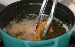 Crispy chicken fingers are delicately lowered into the bubbling oil