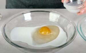 An egg rests gently in a bowl, ready for mixing