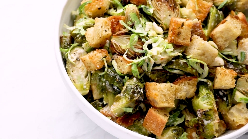 A Bowl of Crispy Brussels Sprout Caesar Salad Topped with Crunchy Croutons and Shredded Sprouts