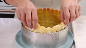 Hands Arranging Ladyfingers Upright Inside a Springform Pan to Prepare the Mold for Charlotte Russe