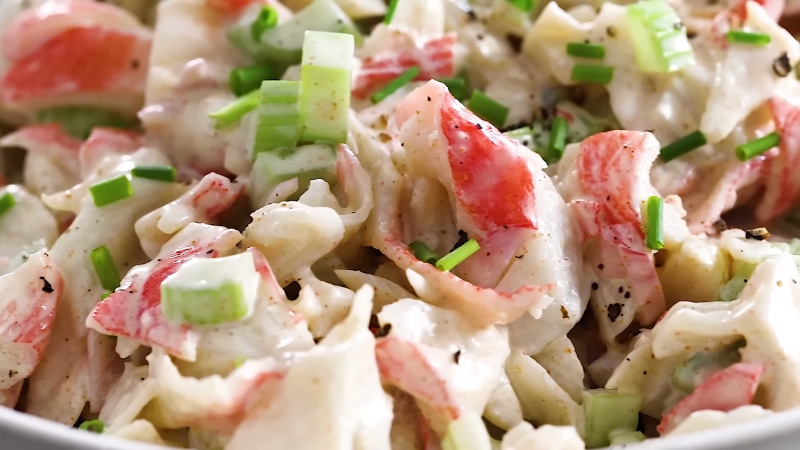 Close-up of imitation crab salad with chopped celery, green onions, and creamy dressing