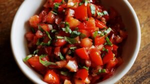 Bowl of diced tomatoes mixed with fresh basil and garlic