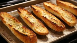 Toasted baguette slices brushed with olive oil and herbs on a baking tray