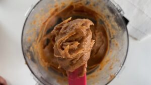 Smooth date caramel on a red spatula over a food processor bowl