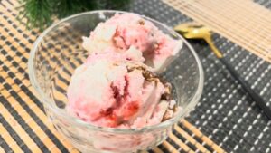 Scoops of strawberry cheesecake cottage cheese ice cream are served in a clear glass bowl
