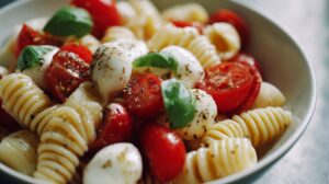 Close-up of a caprese pasta salad with rotini pasta, cherry tomatoes, mozzarella balls, and fresh basil
