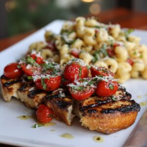 Plate of grilled chicken breast topped with cherry tomato bruschetta, served alongside Caprese pasta salad with basil and Parmesan.