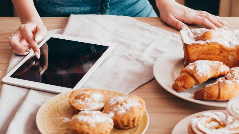 Person taps a tablet beside plated pastries during a cookbook launch setup