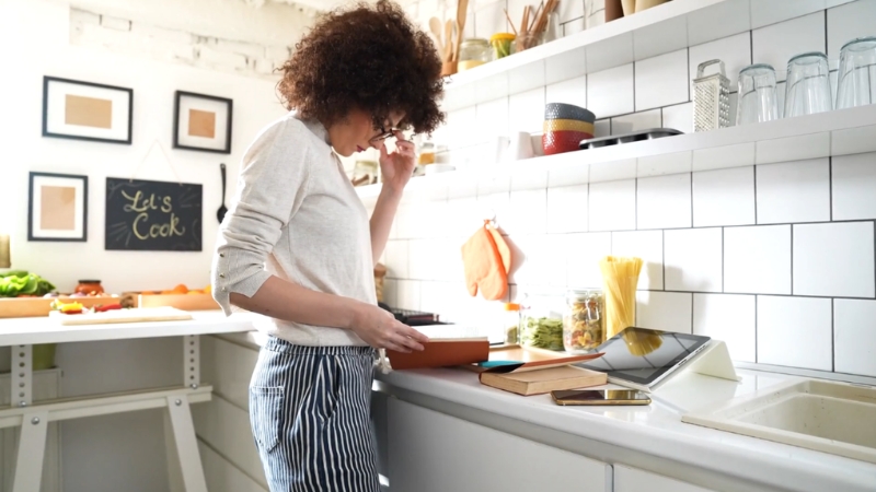 Home cook reviews recipe notes at a kitchen counter while plan for a cookbook takes shape