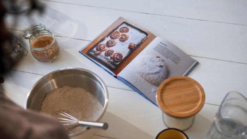Open cookbook beside measured ingredients on a kitchen table during recipe testing