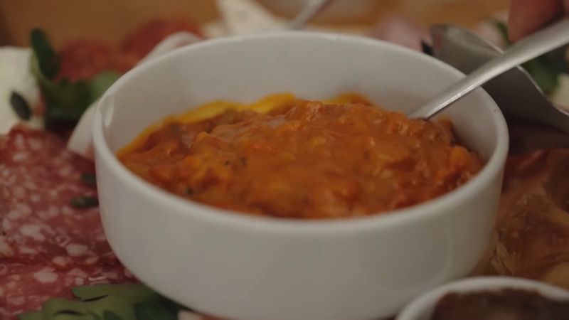 Ajvar served in a white bowl at Ajvar Garden in Ljubljana as part of a shared Balkan table