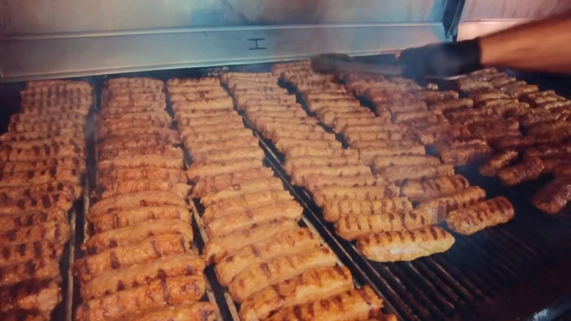 Ćevapi grill at Ćevapčići House in Sarajevo loaded with rows of freshly grilled minced meat