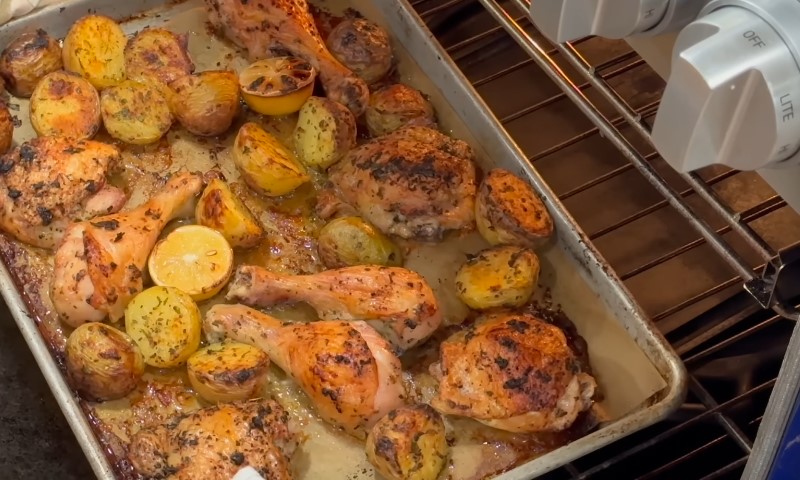Roasted chicken drumsticks and halved potatoes, seasoned and garnished with herbs