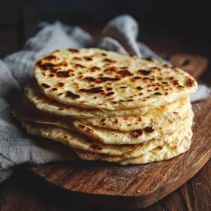 Stack of golden flatbreads on a wooden board
