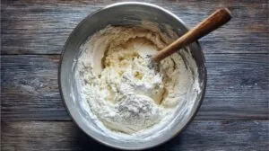 Bowl with flour and yogurt being mixed into dough with a spoon