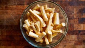 Bowl filled with peeled and cut parsnip pieces on a wooden surface