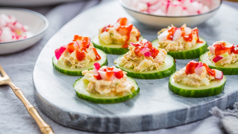 Cucumber slices topped with tuna mixture and diced vegetables on a serving plate