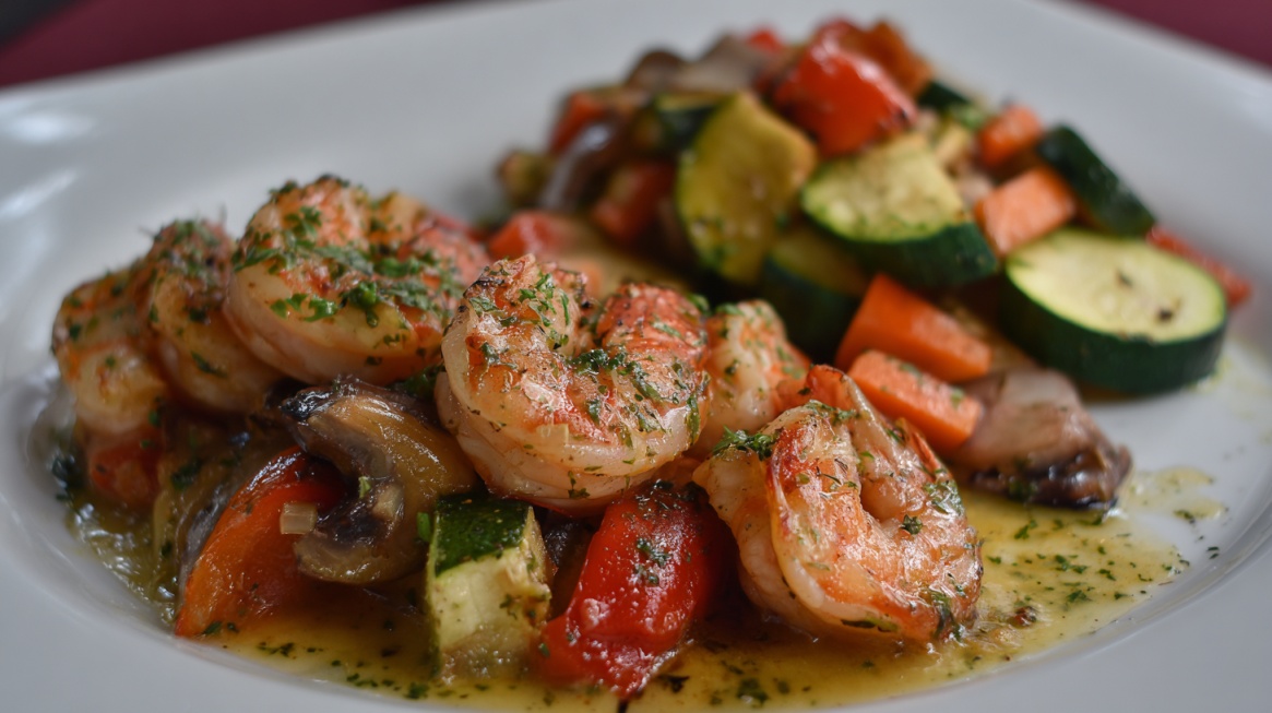 Plate of shrimp with zucchini, carrots, mushrooms, and peppers in a light sauce