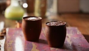 Chocolate phirni poured into traditional clay cups, ready to cool and set before serving
